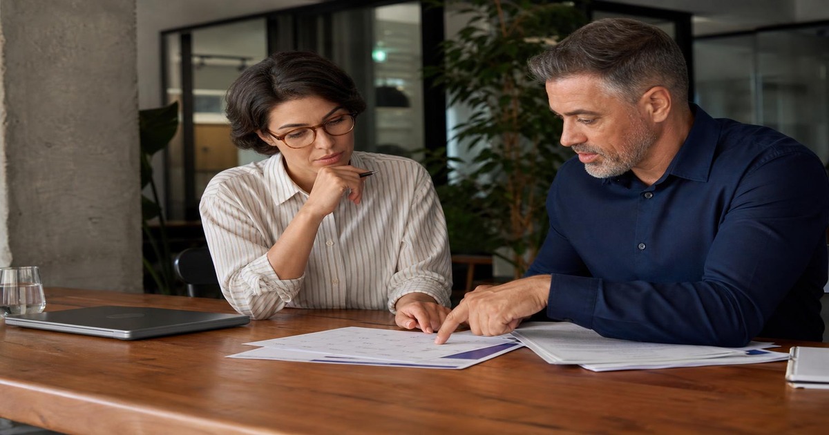 Professional colleagues calmly reviewing competing deadlines and agreeing on a realistic work plan in a modern office.