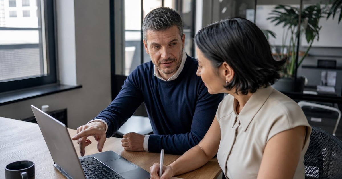 Two office colleagues reviewing a vacation handoff together before one transfers temporary responsibility to the other.