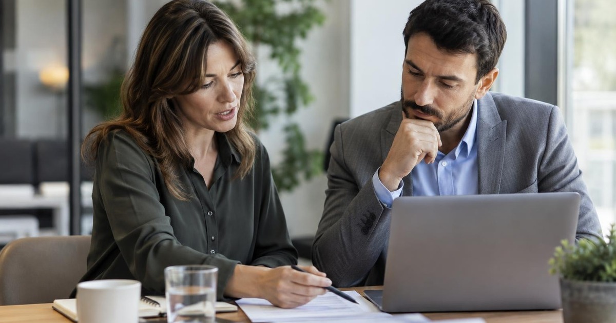 Two adult professionals reviewing an early work deliverable together at a modern office table.