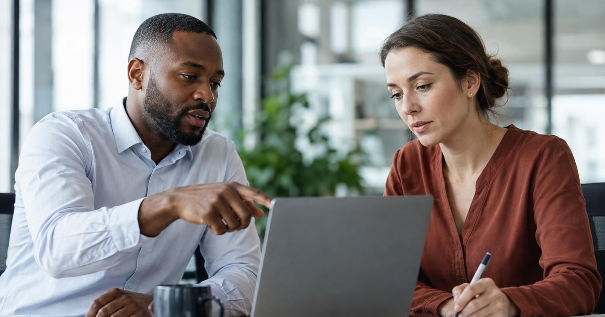Two office professionals reviewing key project assumptions together at a desk before continuing complex work.